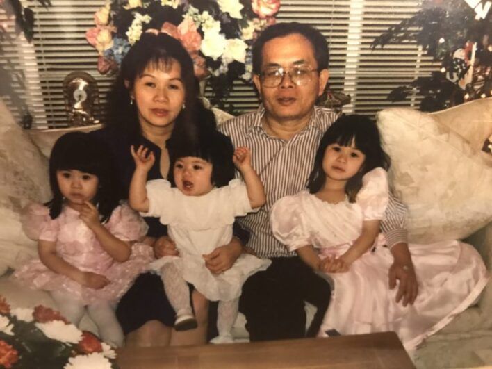 Two people sit on a couch with three young children