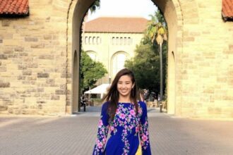 Christine wears a formal dress in front of a stone building