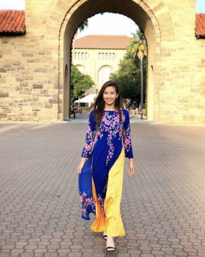 Christine wears a formal dress in front of a stone building