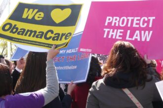 People hold signs in support of ACA