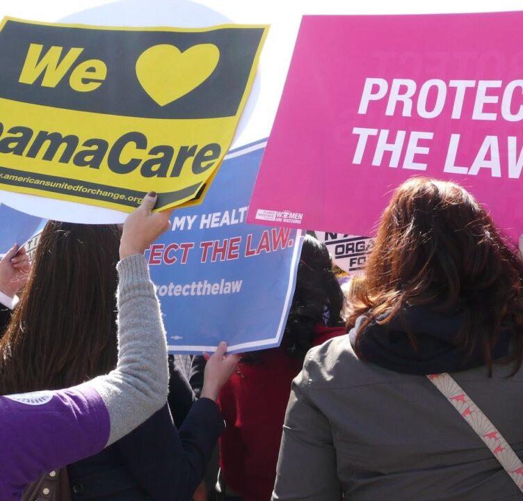 People hold signs in support of ACA