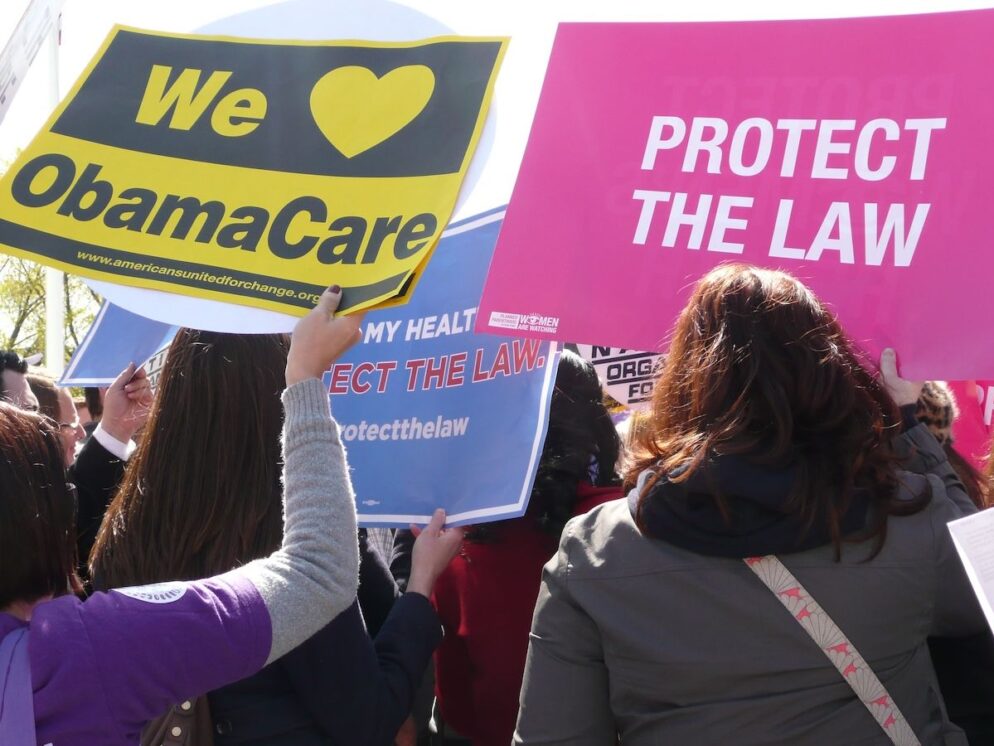 People hold signs in support of ACA