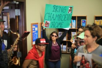 A person holds up a sign saying 