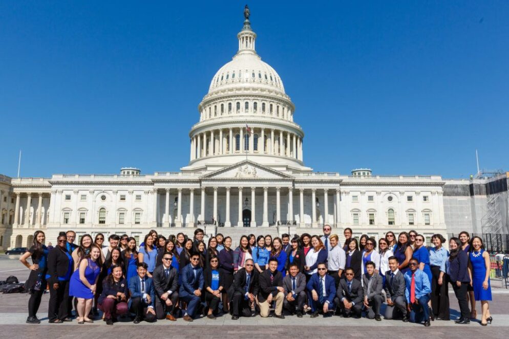 People pose in front of the Capitol building.