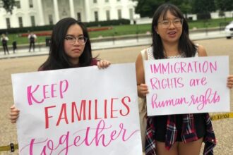 Two people hold up posters