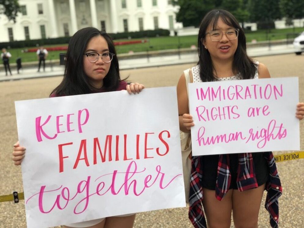 Two people hold up posters