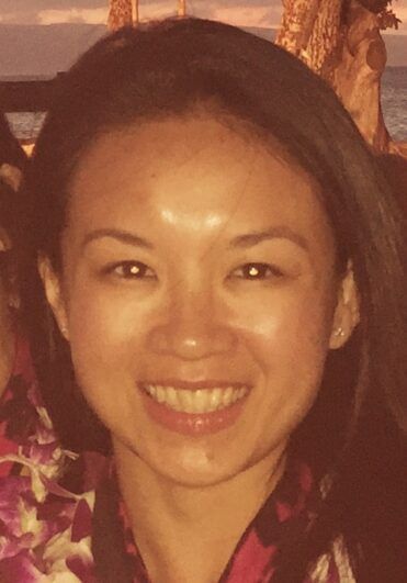 An orange-tone photo of a woman smiling.