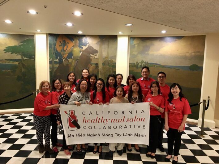 A group of woman standing for a group picture while holding a sign that says "California Healthy Nail Salon Collaborative"