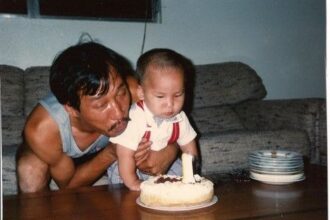 An old photograph of the author of this blog post, Eric La Nguyen, as a toddler blowing out a birthday cake candle with his dad.