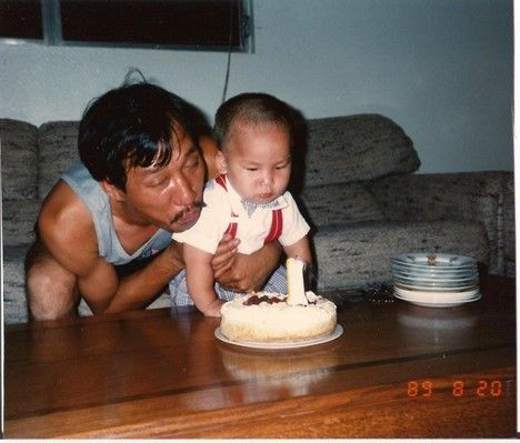 An old photograph of the author of this blog post, Eric La Nguyen, as a toddler blowing out a birthday cake candle with his dad.