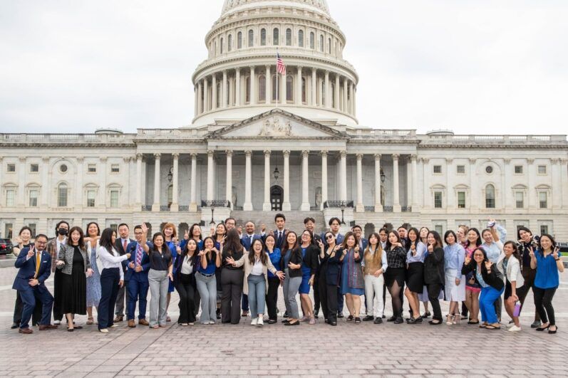 Dozens of individuals pose in front of the Capitol building