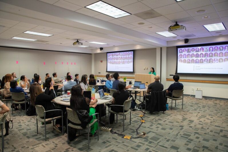 Individuals sit around tables in a conference room.