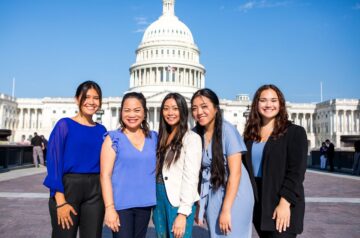 5 individuals stand in front of the US Capitol Building