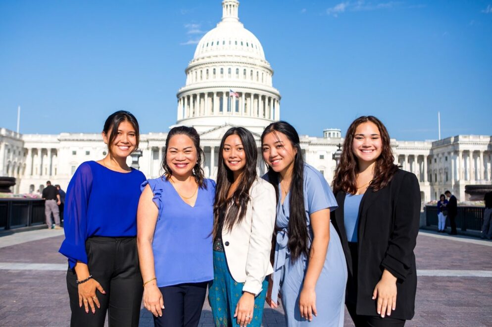 5 individuals stand in front of the US Capitol Building