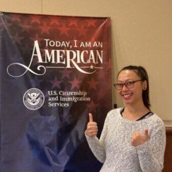 Lundy giving a thumbs up in front of a USCIS sign.