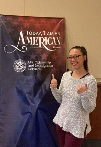 Lundy giving a thumbs up in front of a USCIS sign.