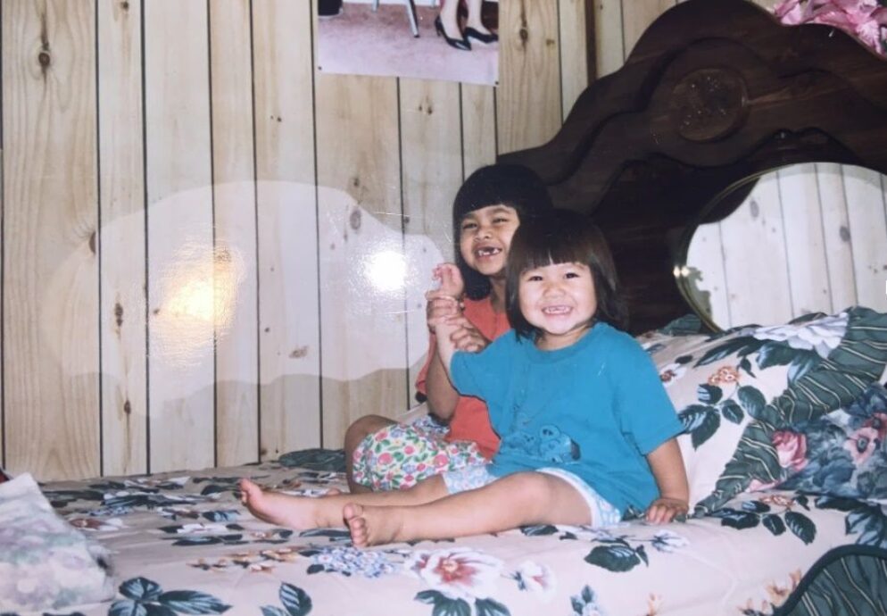 Nary as a small child sitting on a bed.