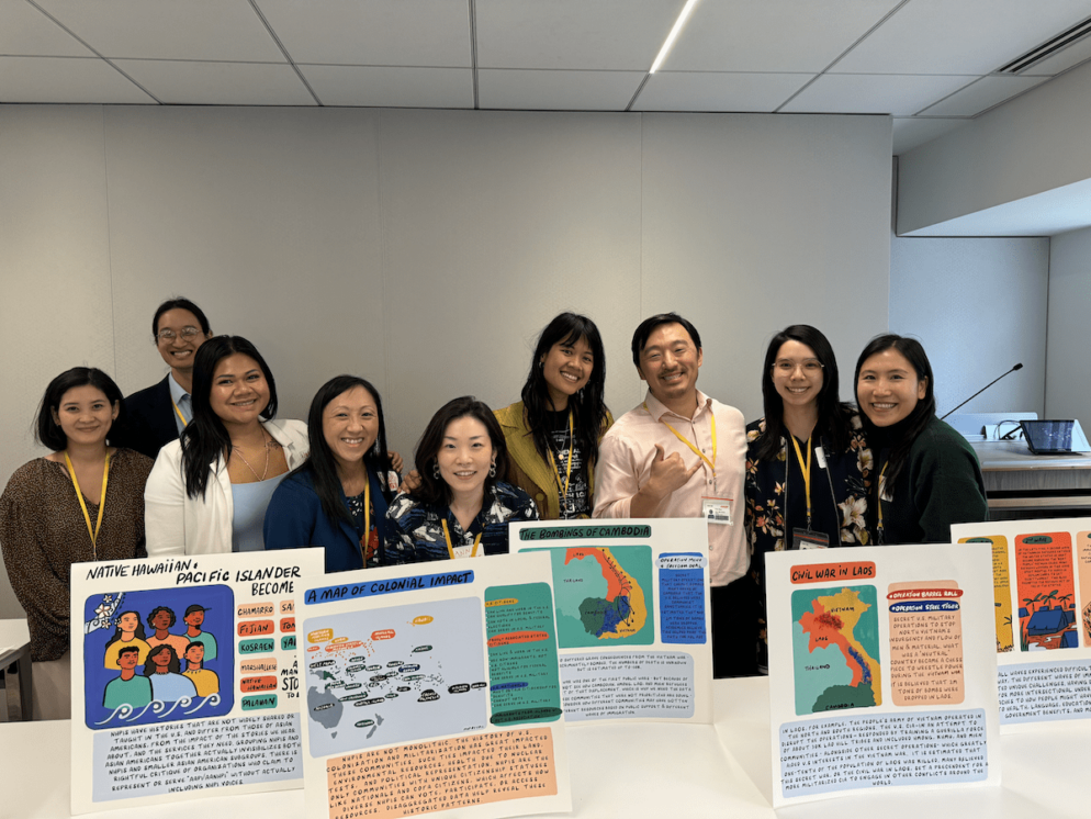 A group of people stand behind a conference table containing art prints.