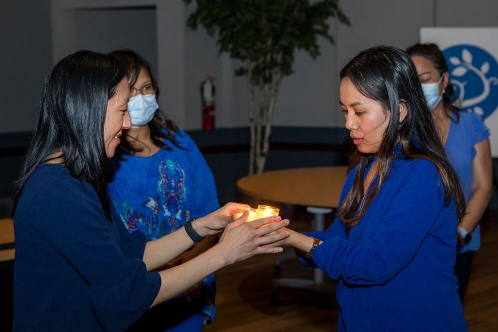 Quyen holds a candle together with another individual.