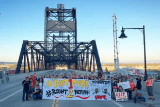 People stand on a bridge holding signs