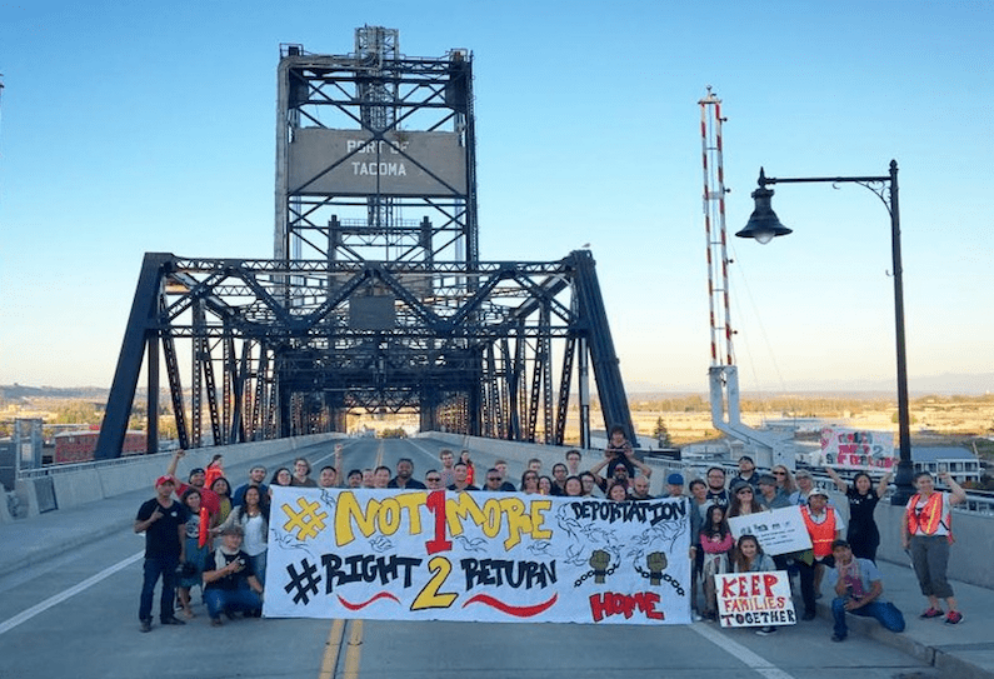 People stand on a bridge holding signs