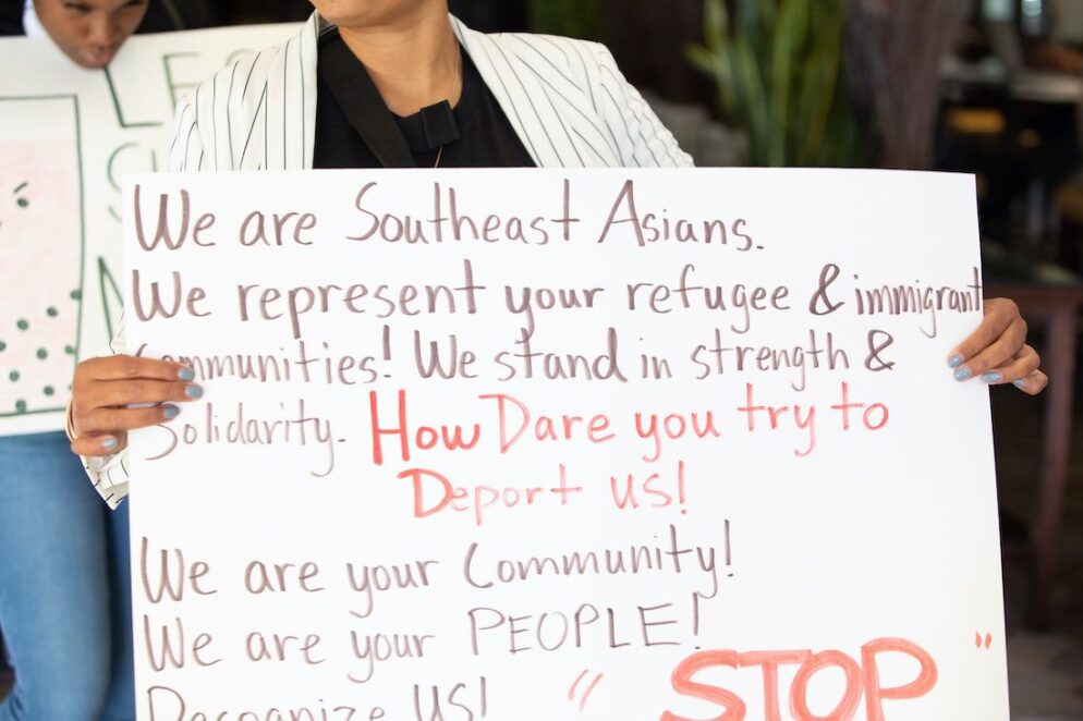 A person holding a sign with black texts.