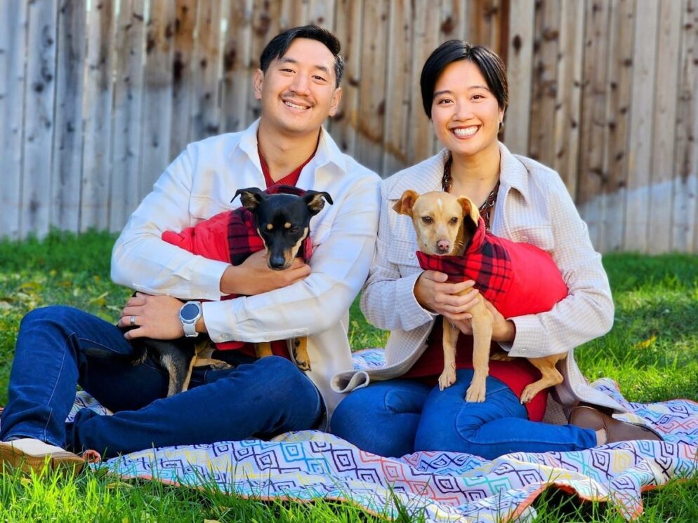 Two people smiling, each holding dogs