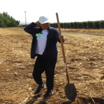 Mary holds a shovel at a field