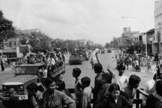 Cambodians raising their fists on moving vehicles.