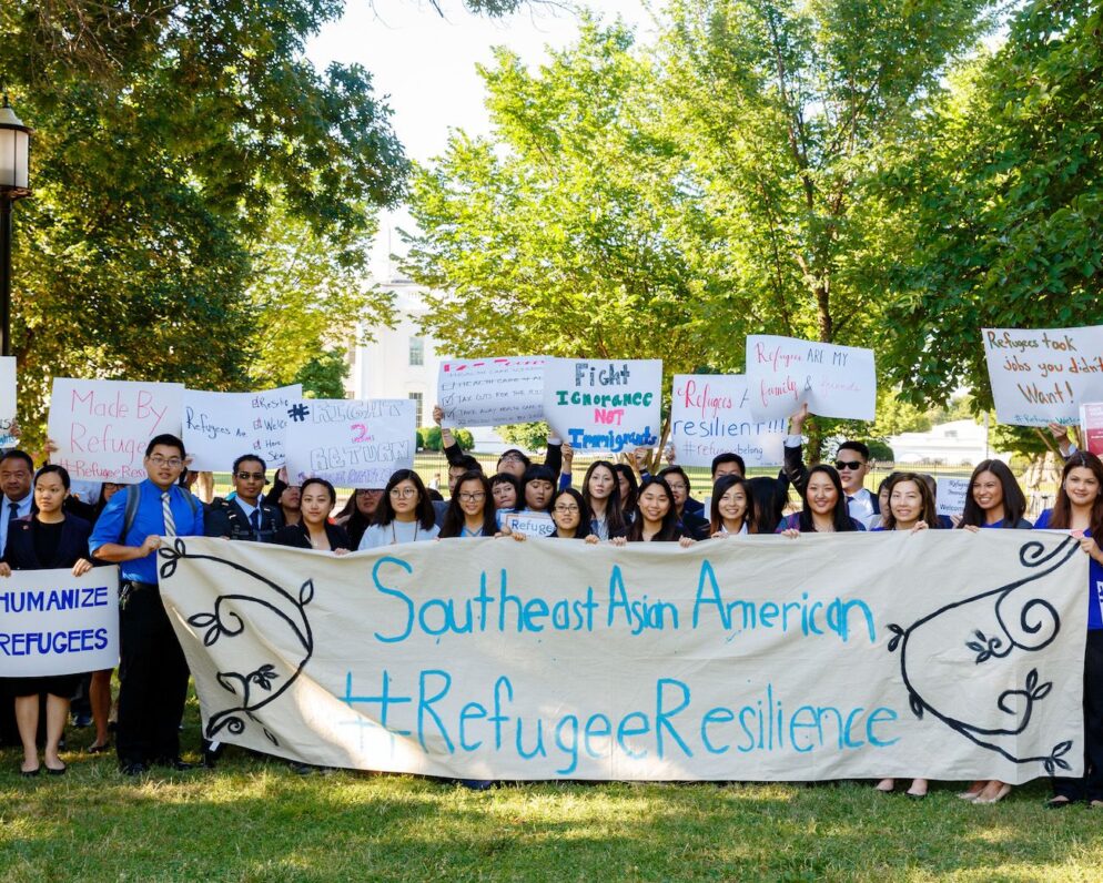 People hold up a stating Southeast Asian Refugee Resilience banner