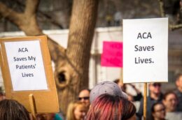 People hold up signs in support of ACA