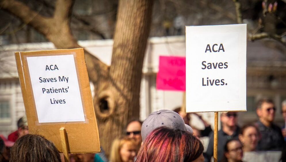 People hold up signs in support of ACA