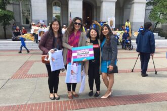 Four people, one holding a sign saying Health 4 All