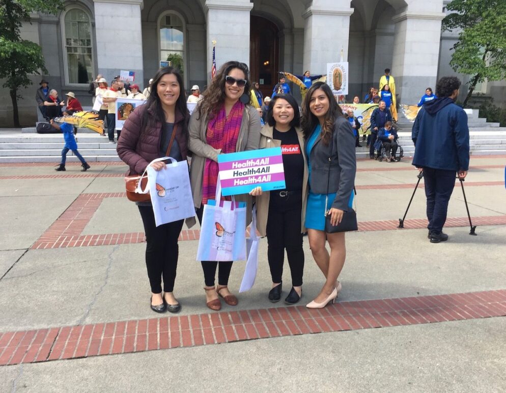 Four people, one holding a sign saying Health 4 All