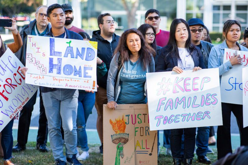 People hold signs at an anti-deportation rally