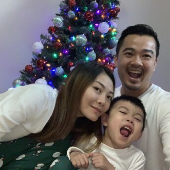 family poses in front of Christmas tree