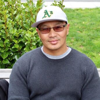 Danny sitting on a bench, smiling at the camera