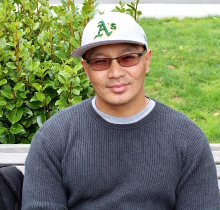 Danny sitting on a bench, smiling at the camera