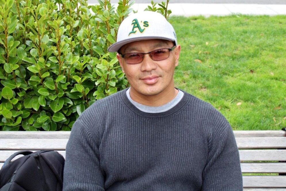 Danny sitting on a bench, smiling at the camera