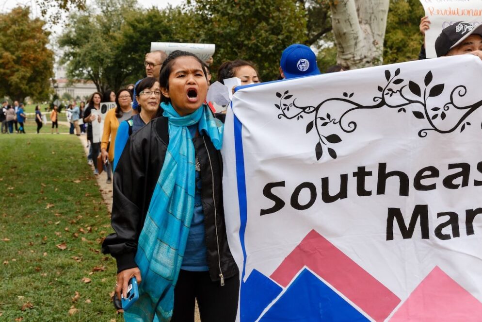 Person holds a banner and stands at the front of a march