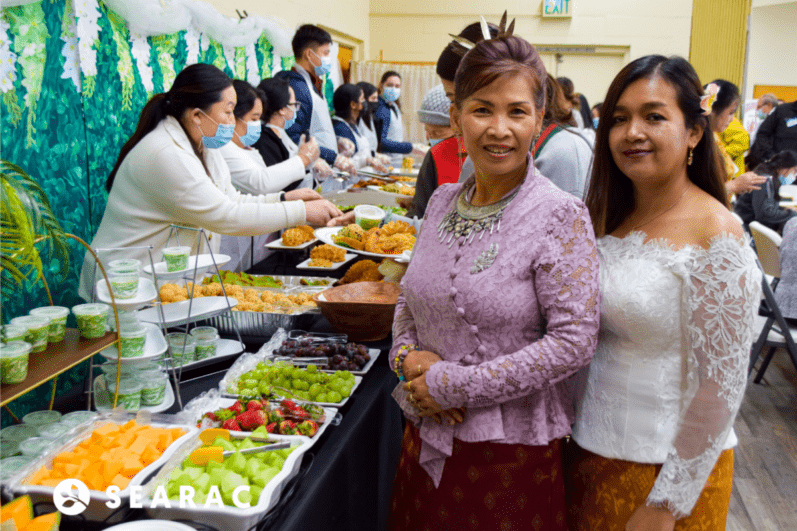 Women standing by entrees of food.