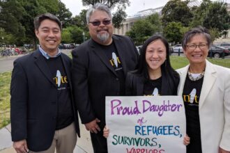 Quyen holding a poster showing her proud identity as a daughter of refugees.