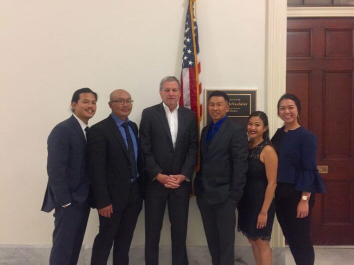 Ke poses with others in front of an American flag