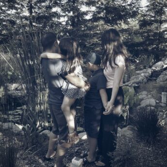 family looks away from camera in a wooded area