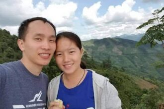 Moua and Dokmai smiling into the camera with mountains behind them.