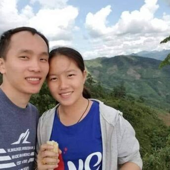 Moua and Dokmai smiling into the camera with mountains behind them.