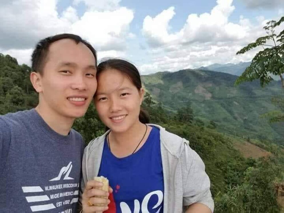 Moua and Dokmai smiling into the camera with mountains behind them.