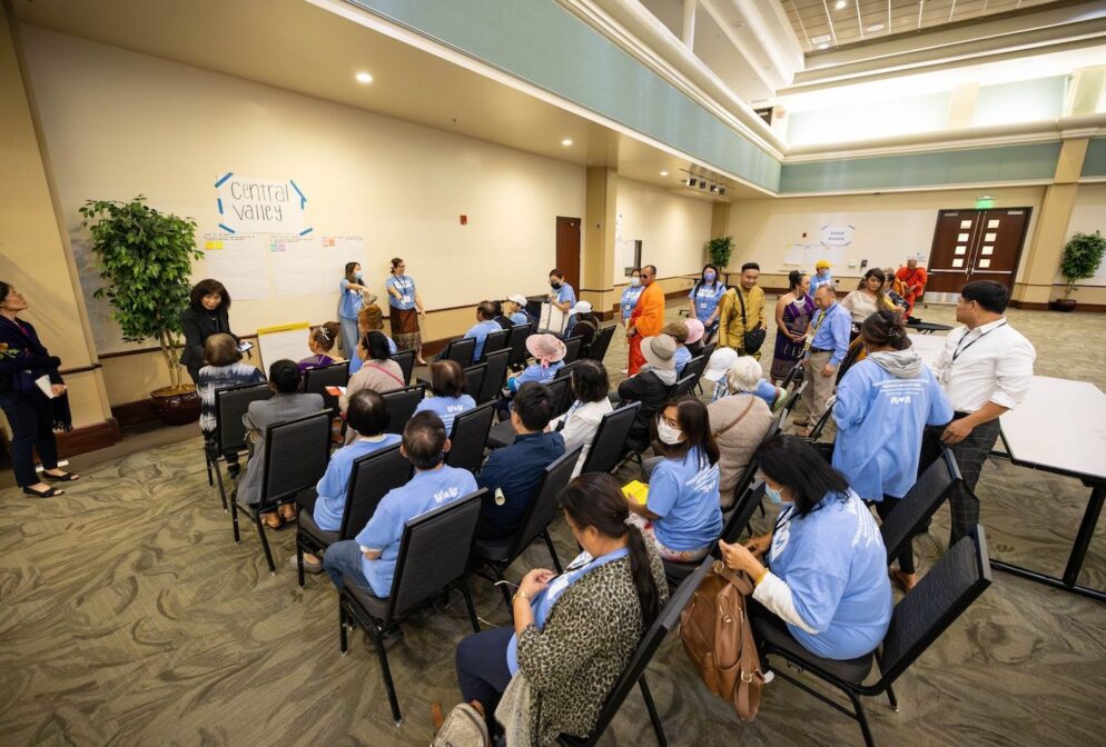 People, many in blue shirts, sit in a conference room