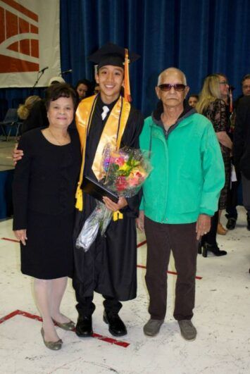 A grandson posing with his grandparents during his graduation