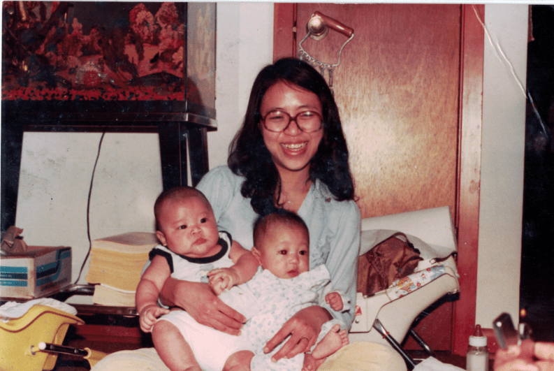 Smiling woman wearing glasses holds two babies